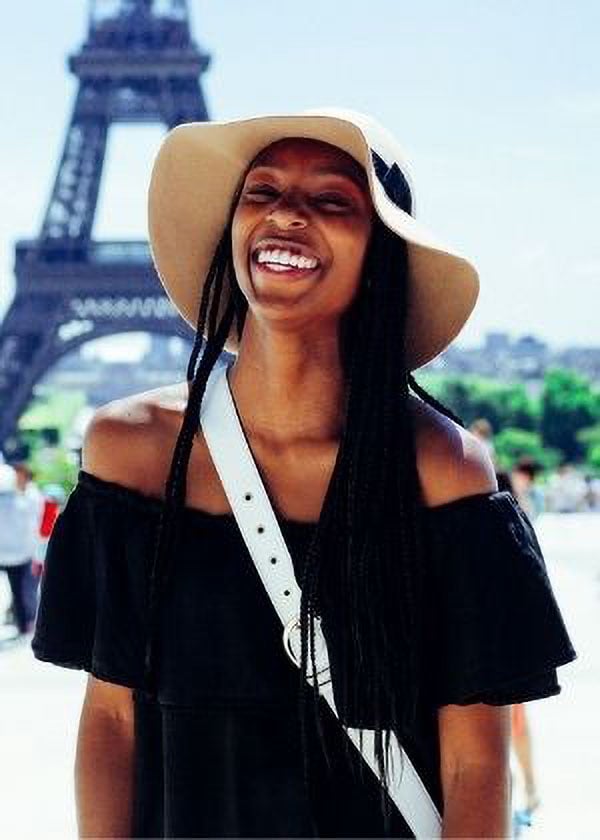 A young woman stands in front of the Eiffel Tower